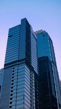 Tall glass skyscrapers under a blue sky, showcasing urban architecture.