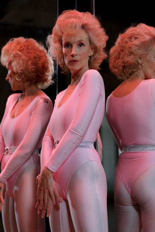 Woman in Pink Leotard and Leggings Standing beside Mirror