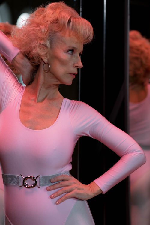 Free Senior woman posing gracefully in a dance studio, wearing a leotard with mirror reflection. Stock Photo