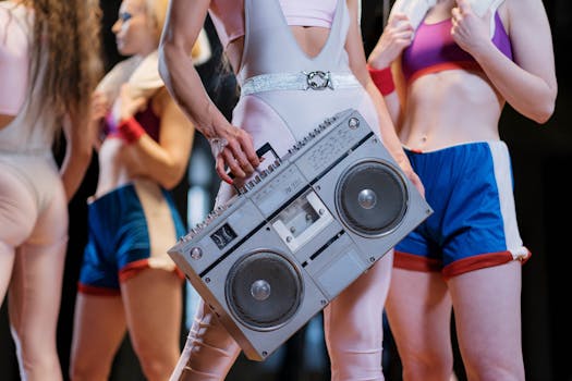 Group of women in retro workout clothes holding a vintage boombox indoors.