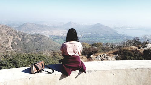 Woman Wearing Pink Shirt Sitting on Gray Concrete Rail