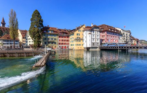 Free Colorful buildings reflecting in the river, showcasing a picturesque Swiss town scene. Stock Photo