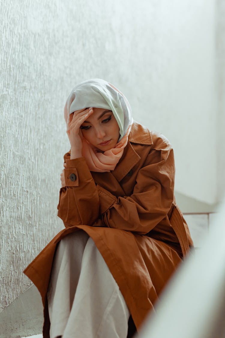 A Sad Woman In A Hijab And A Brown Coat