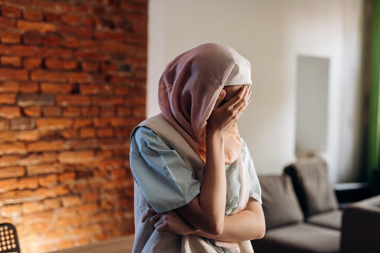 Woman Wearing Headscarf Covering Face With One Hand