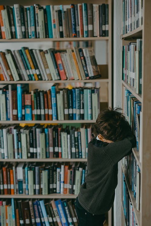 
A Boy Leaning on a Bookshelf