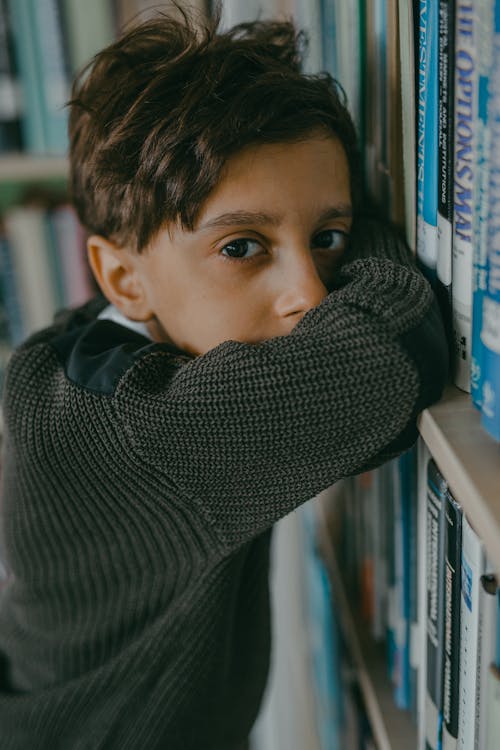 A Boy Leaning on a Bookshelf