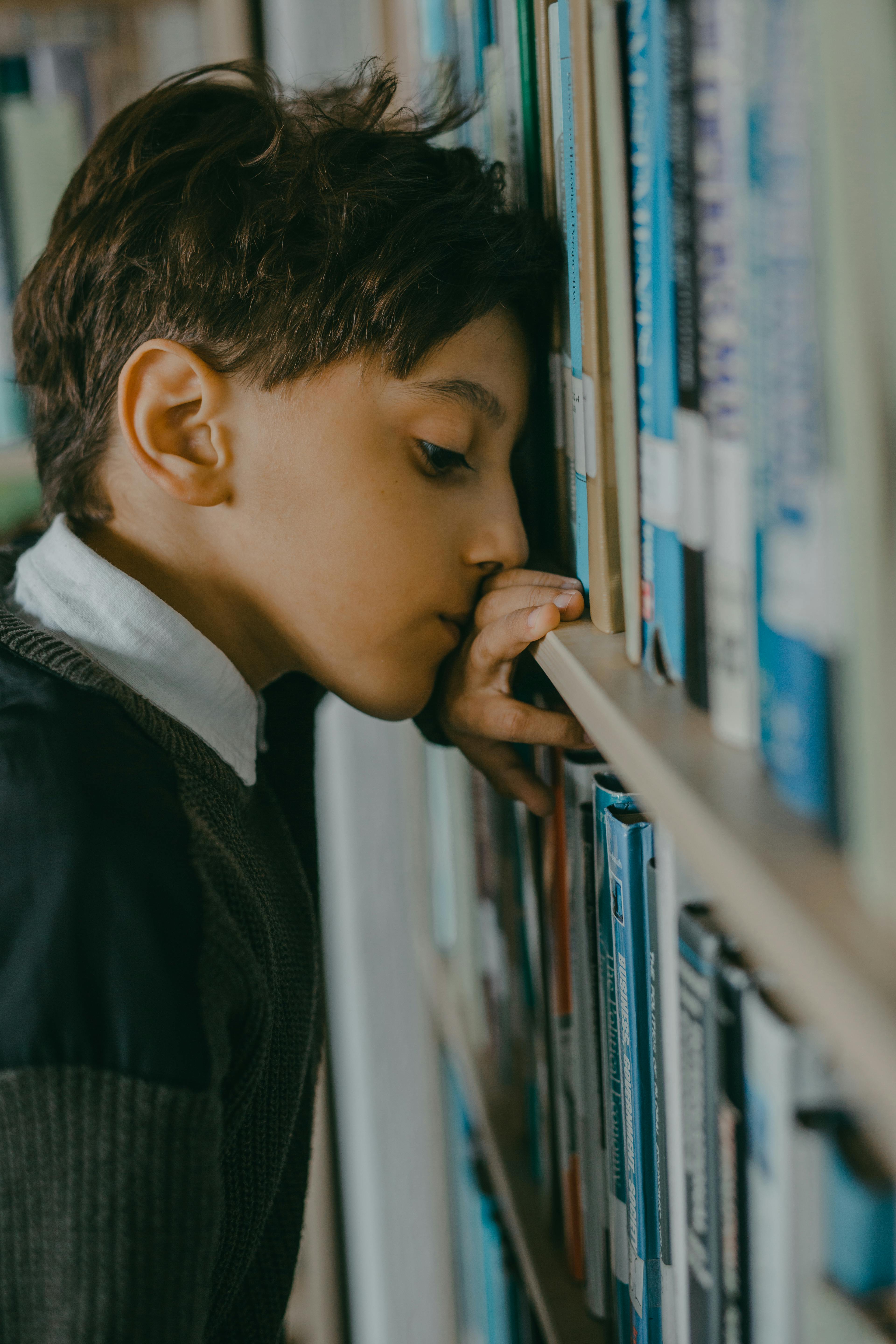 depressed boy leaning on a bookshelf