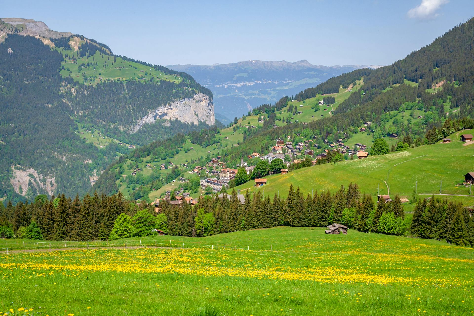 Picturesque landscape of Swiss countryside with lush green hills and wooden houses.