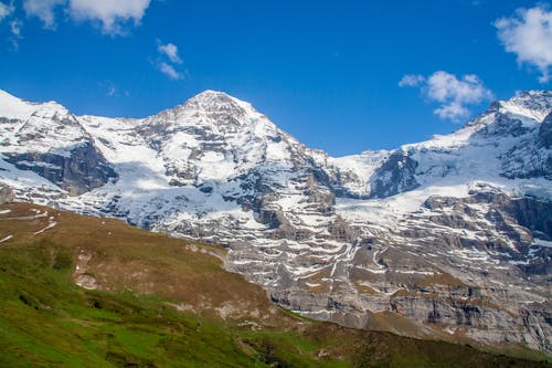 Snow Capped Mountains Near Green and Brown Mountain