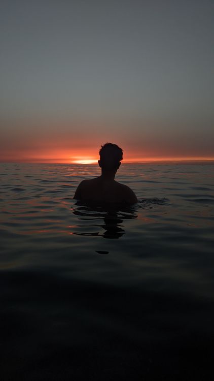 Silhouette of a Man in the Sea at Dawn · Free Stock Photo
