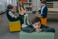 Boy in Black and White Striped Long Sleeve Shirt Sitting on Green Chair