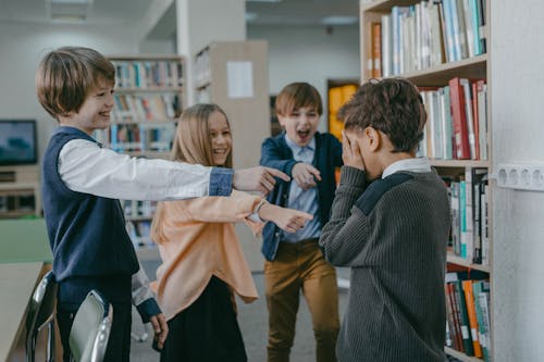 Free A Group of Children Laughing at a Boy in a Library Stock Photo