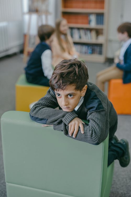Free Child gazes thoughtfully in a classroom environment, surrounded by peers. Stock Photo