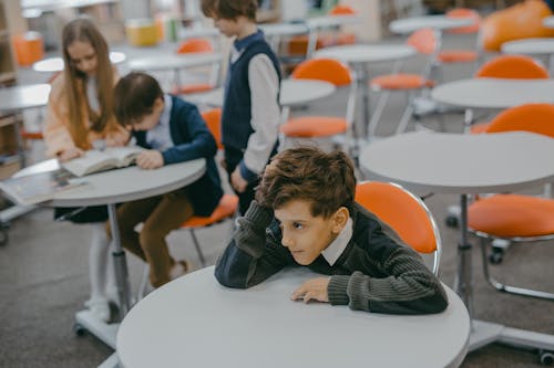 A Boy Sitting Alone Away From Fellow Students