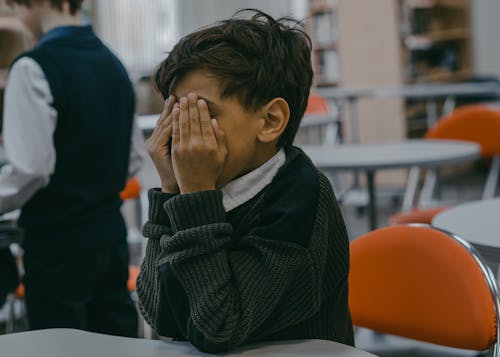 A Boy Covering His Face with His Hands