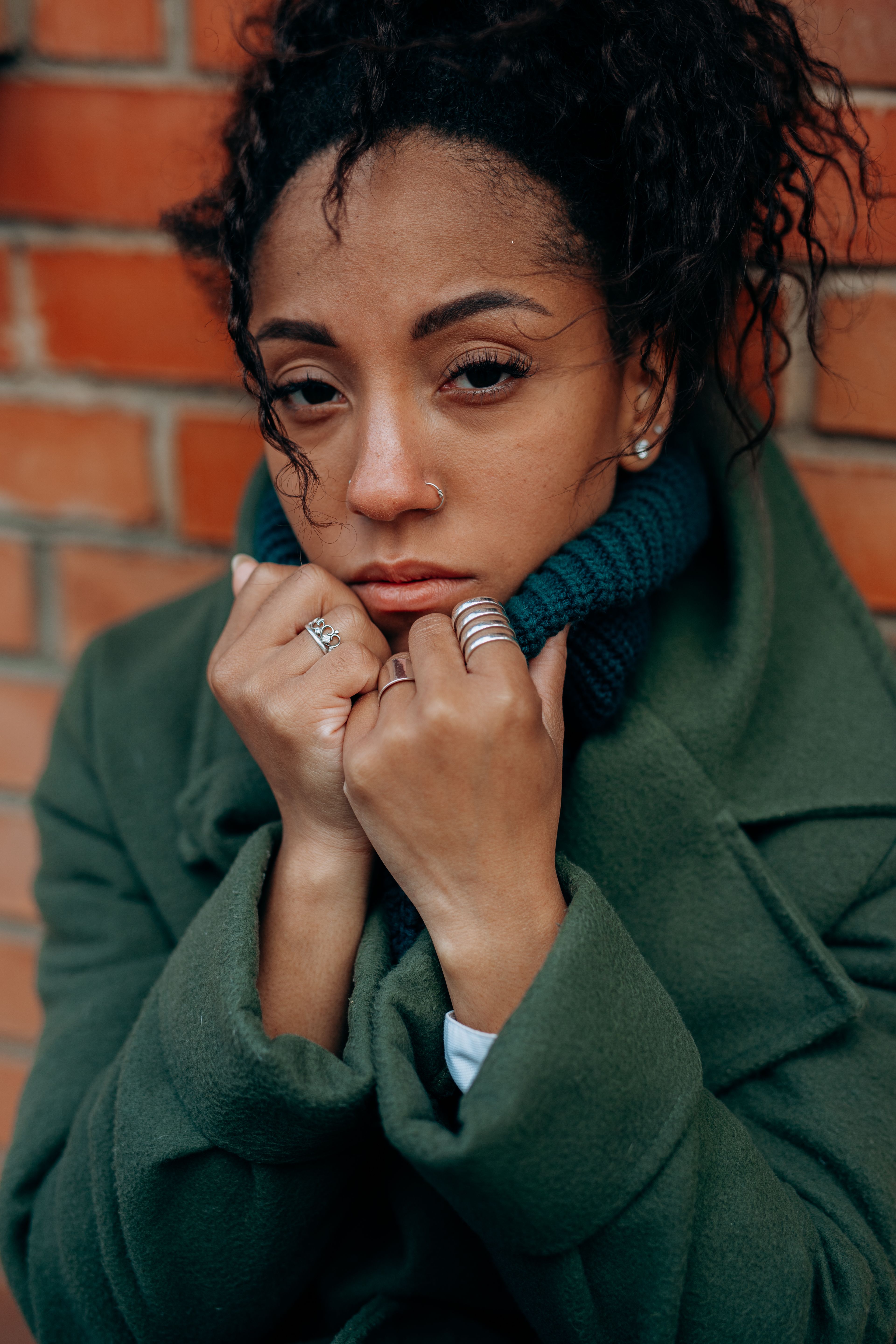 Woman in Green Jacket Standing beside Brown Brick Wall · Free Stock Photo