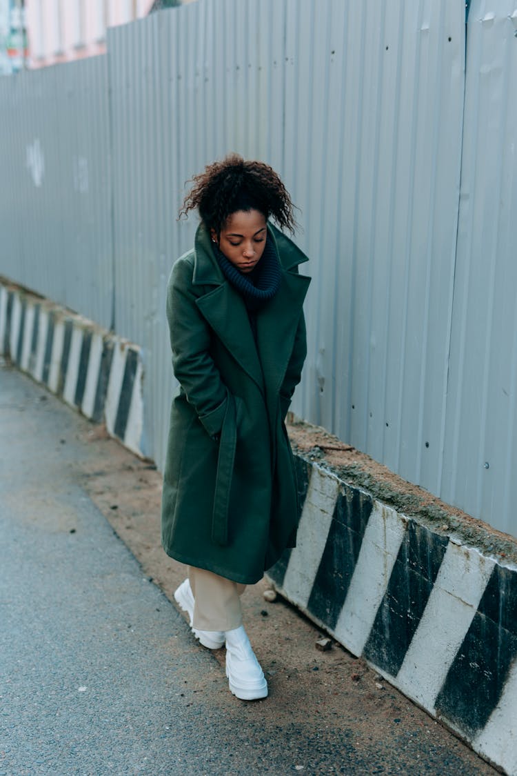 Sad Woman In Green Trench Coat Walking On A Street