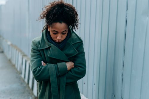 Free A woman stands in contemplation wearing a green coat on a cool day outdoors. Stock Photo