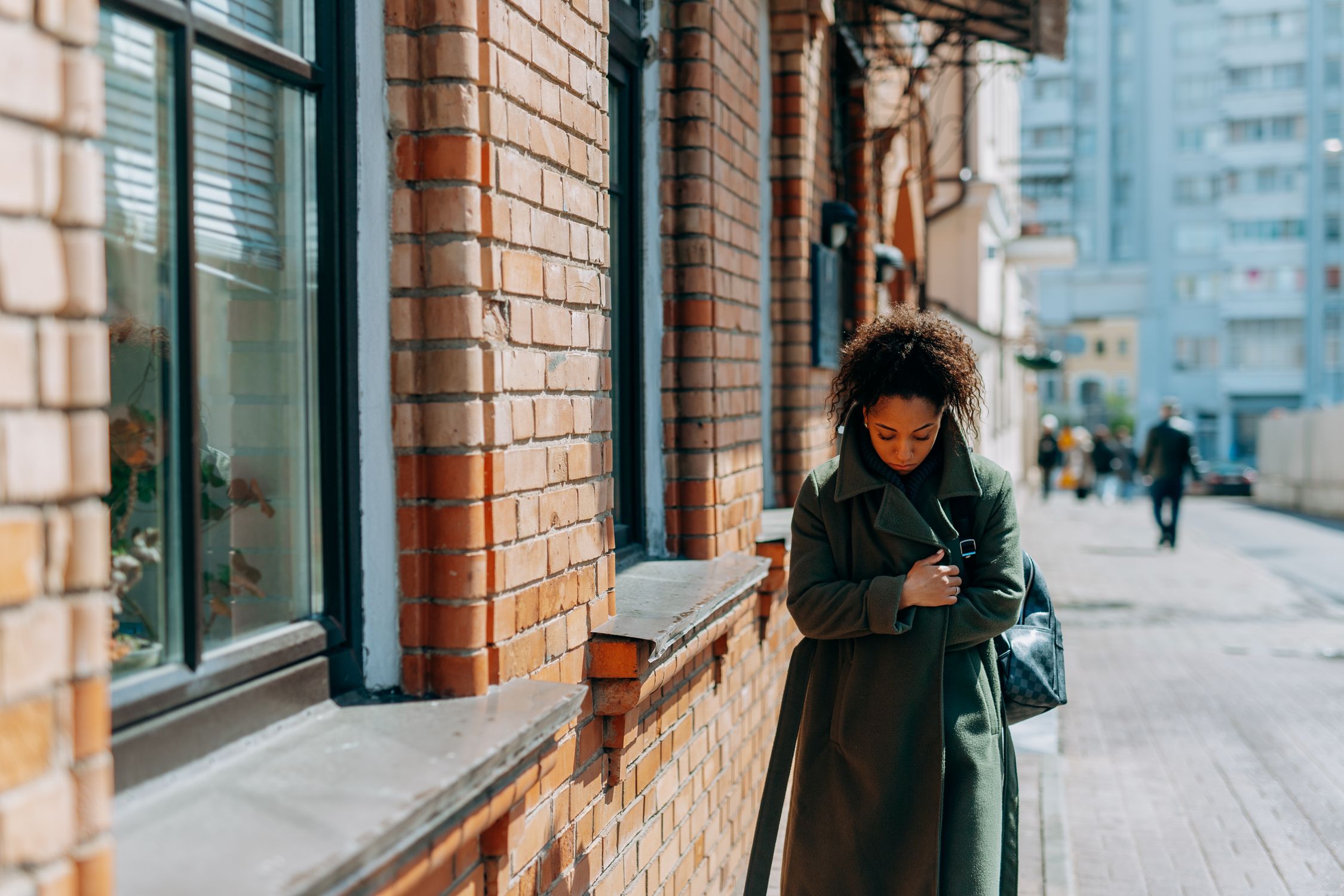 Woman in Brown Coat Standing Near Brown Brick Wall · Free Stock Photo