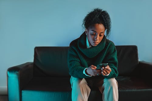 A Woman in Green Sweater Sitting on Black Couch