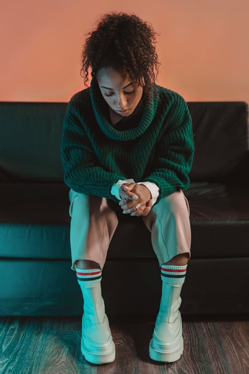 A Woman in Green Sweater Sitting on Black Couch