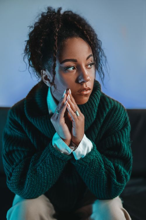 Free Thoughtful young woman in a green turtleneck sweater with serene expression. Stock Photo