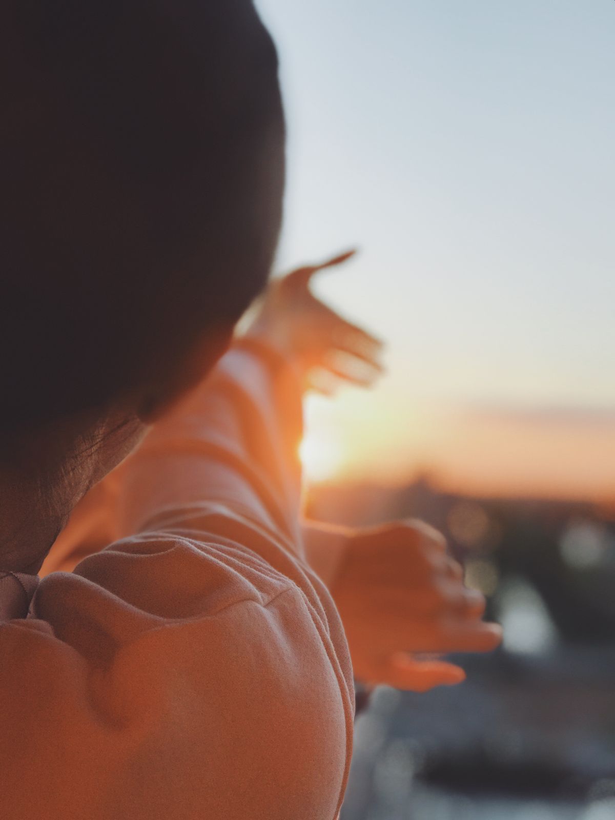 Silhouette of a woman with arms raised toward the sunrise, symbolizing hope and moving forward