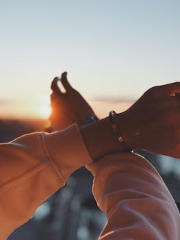 A close-up view of outstretched arms capturing the scenic sunset with a blurred background.