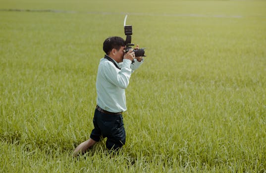 Photographer takes pictures in a lush green field on a sunny day, showcasing rural beauty.
