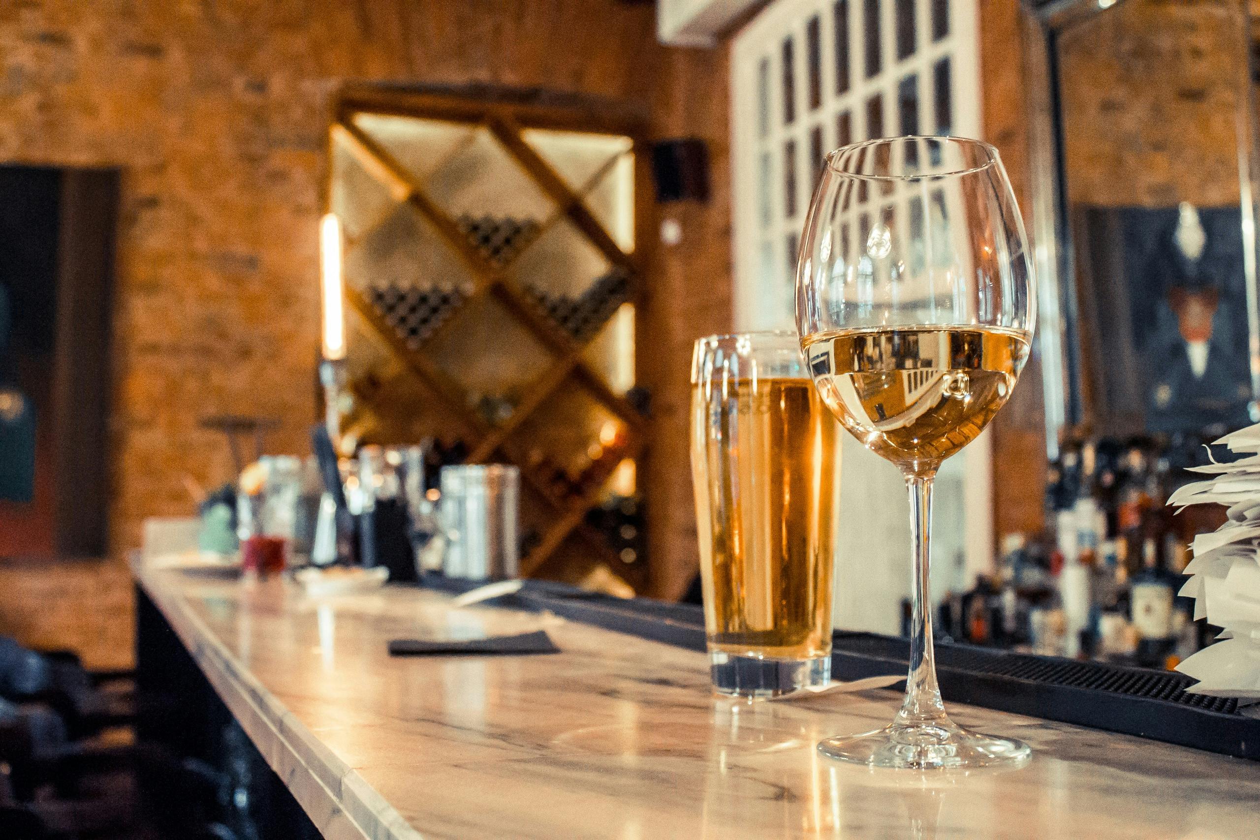 A selection of craft beers and New Zealand wines, arranged on a bar with a blurred background of a busy restaurant