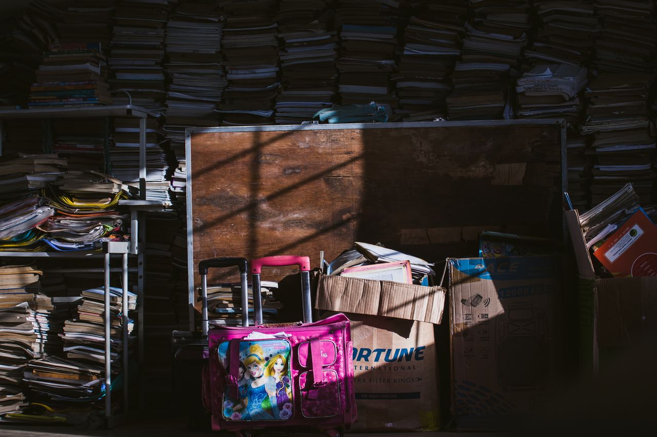 A dimly lit room with stacks of books and boxes, casting dramatic shadows.
