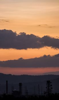 Dramatic skyline with silhouetted power lines and industrial structures against a vibrant sunset.