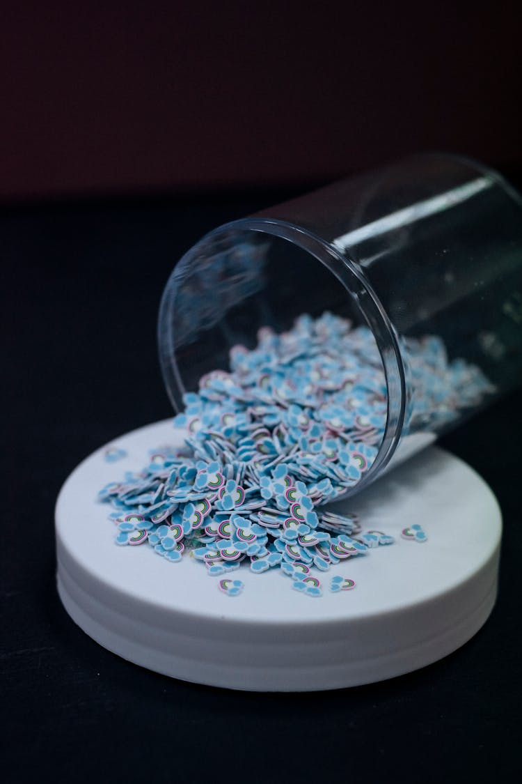 Blue Plastic Chips Spilling From Glass Container