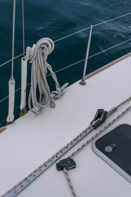 Free Close-up of sailing yacht deck featuring ropes, metal railing, and ocean view. Stock Photo