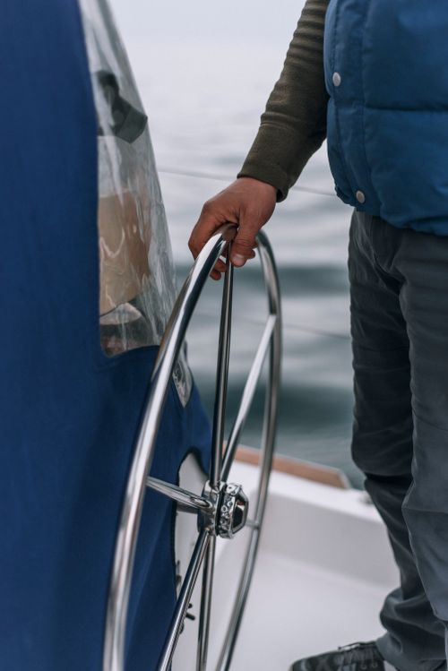 Free A person steering a boat using a chrome helm, showcasing maritime control. Stock Photo