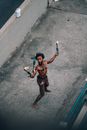 From above of ethnic shirtless and barefoot homeless male fakir juggling burning torches on street