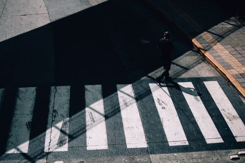 Free From above full body of anonymous man in shadow strolling on crosswalk of road in sunny day Stock Photo