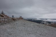 雪道旁，一个孤独的人行走在优美的风景和多云的天空下