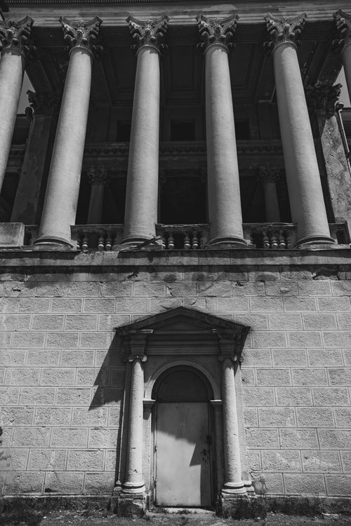 Free Black and white photo of classical building facade with tall columns and arched doorway. Stock Photo