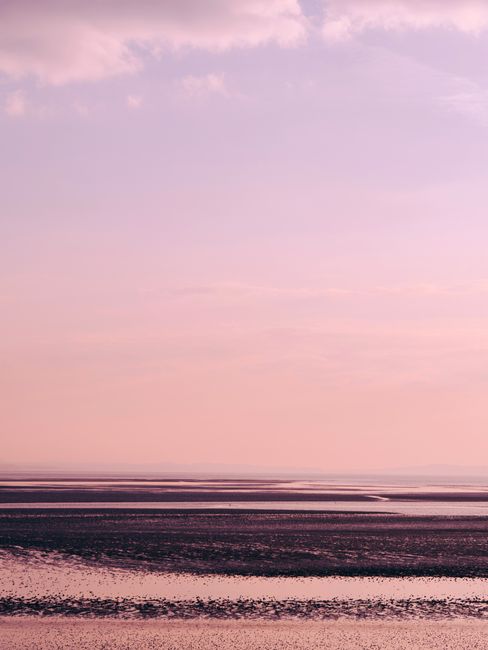 A tranquil view of mudflats under a pastel sky, captured during twilight.
