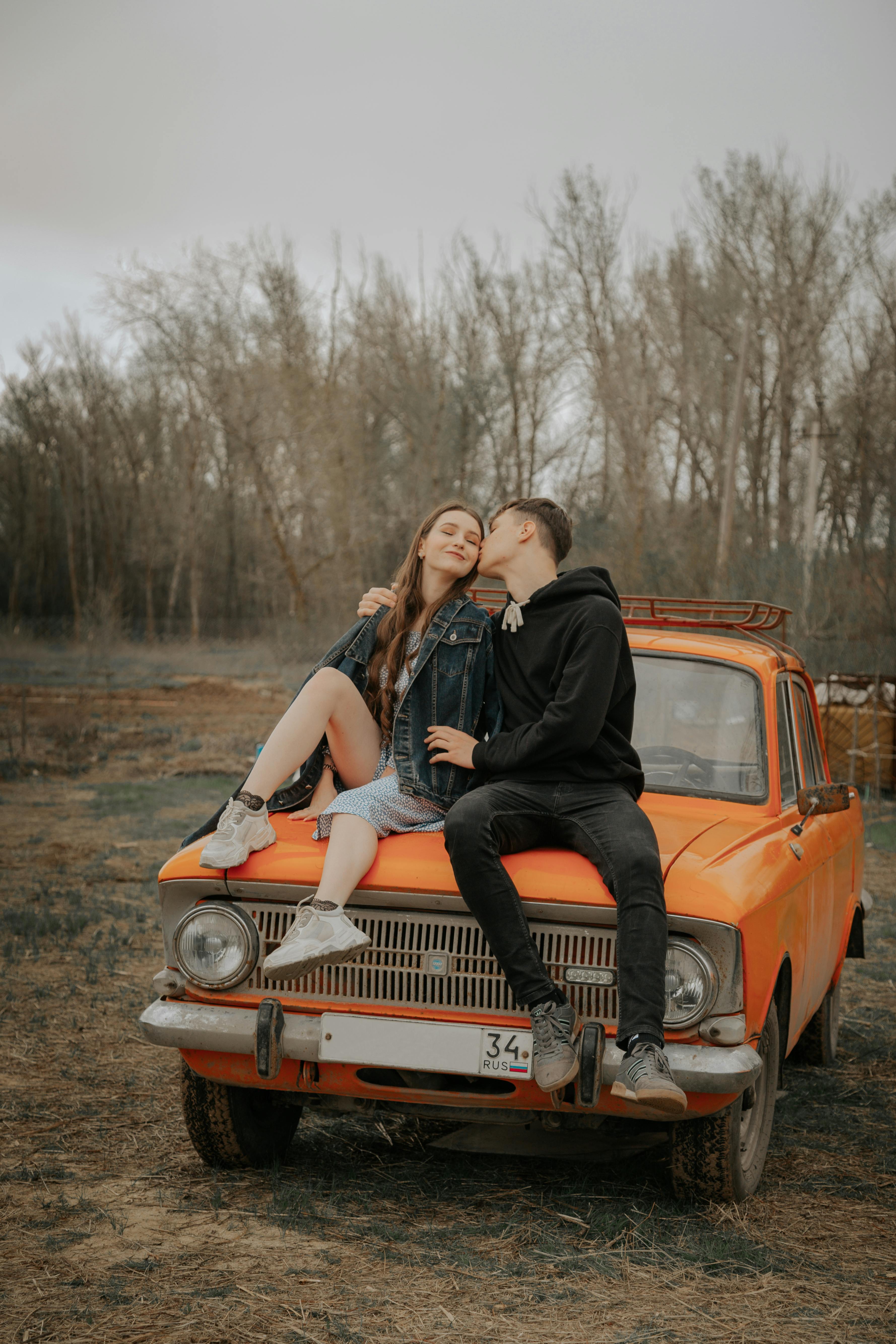 cool couple embracing on old car in autumn countryside