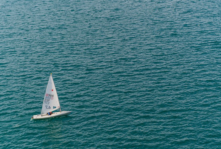 A lone sailboat glides across the tranquil blue ocean, capturing a moment of solitude and adventure.