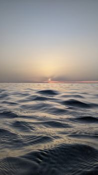 Peaceful ocean view at sunset with gentle waves, captured outdoors in Algeria.