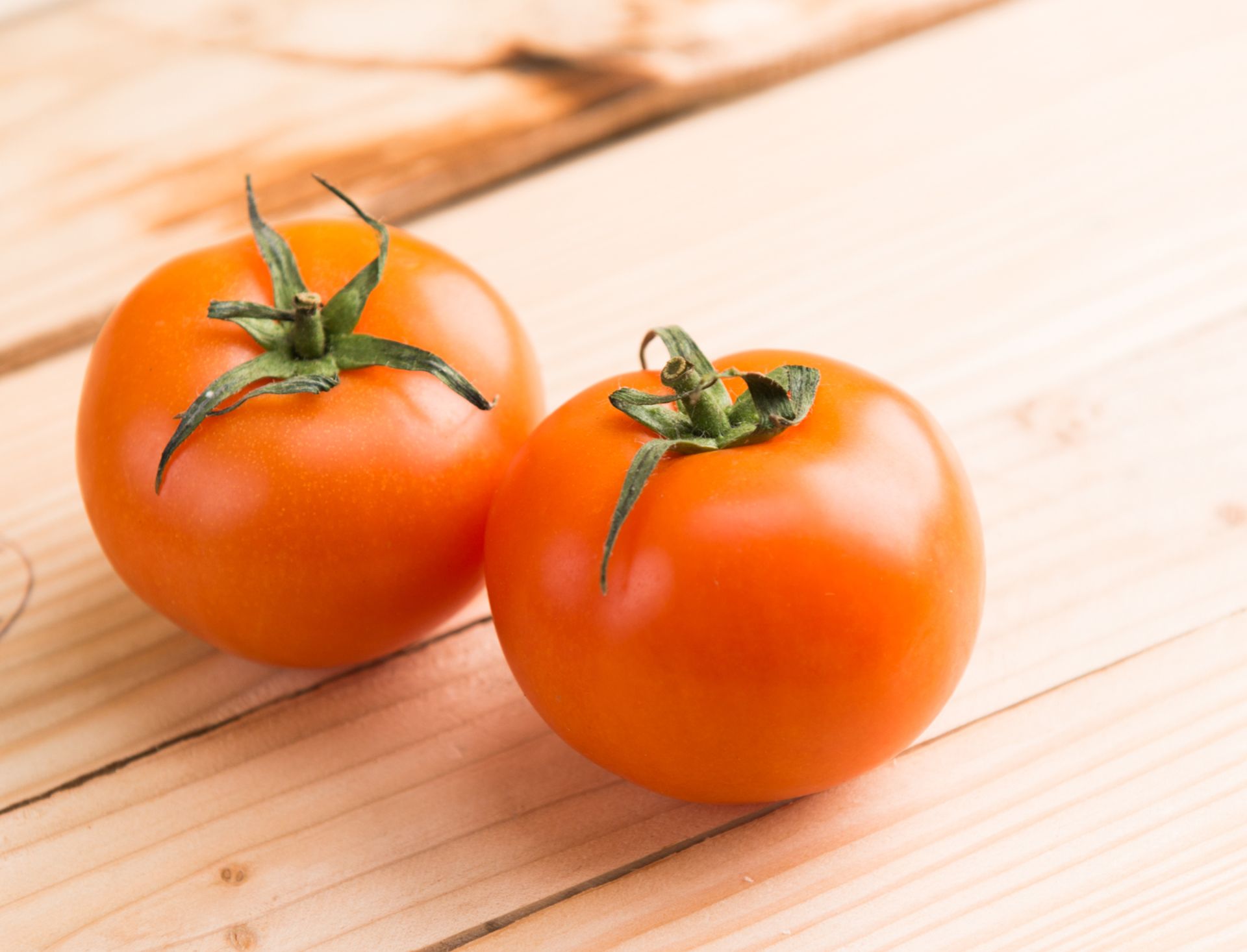 Close-up of two fresh tomatoes on a wooden table representing healthy eating.