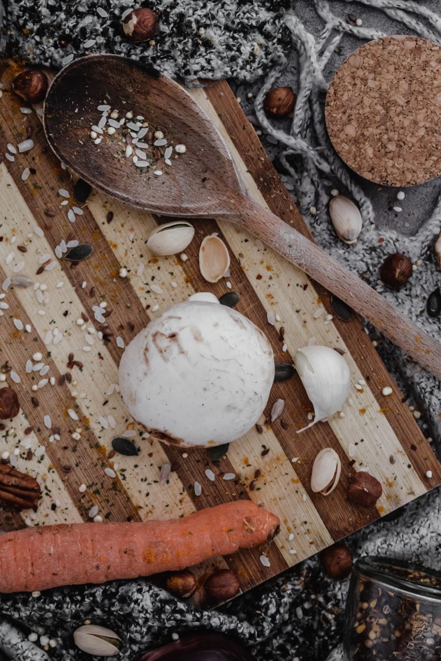 Top view of a rustic kitchen setup featuring a wooden spoon, chopping board, and vegetables.