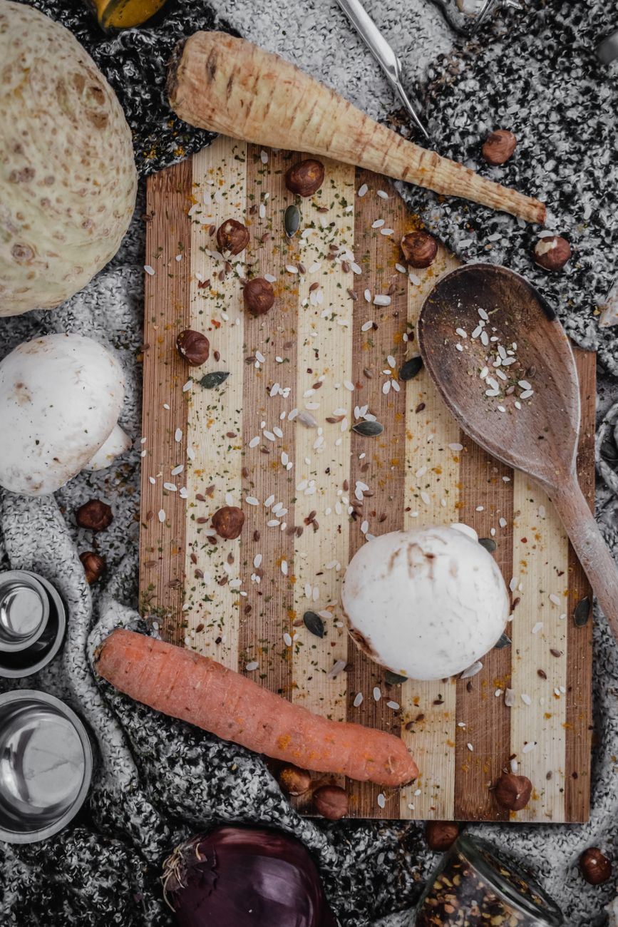 Top view of vegetables and wooden spoon on a rustic cutting board, ideal for culinary themes.