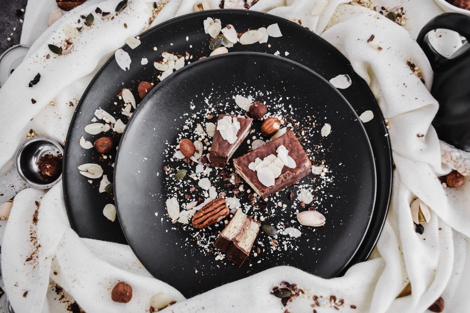 A pan of seven layer bars cut into squares, showing layers of graham cracker crust, melted chocolate and butterscotch chips, toasted coconut, and chopped pecans pressed into sweetened condensed milk.