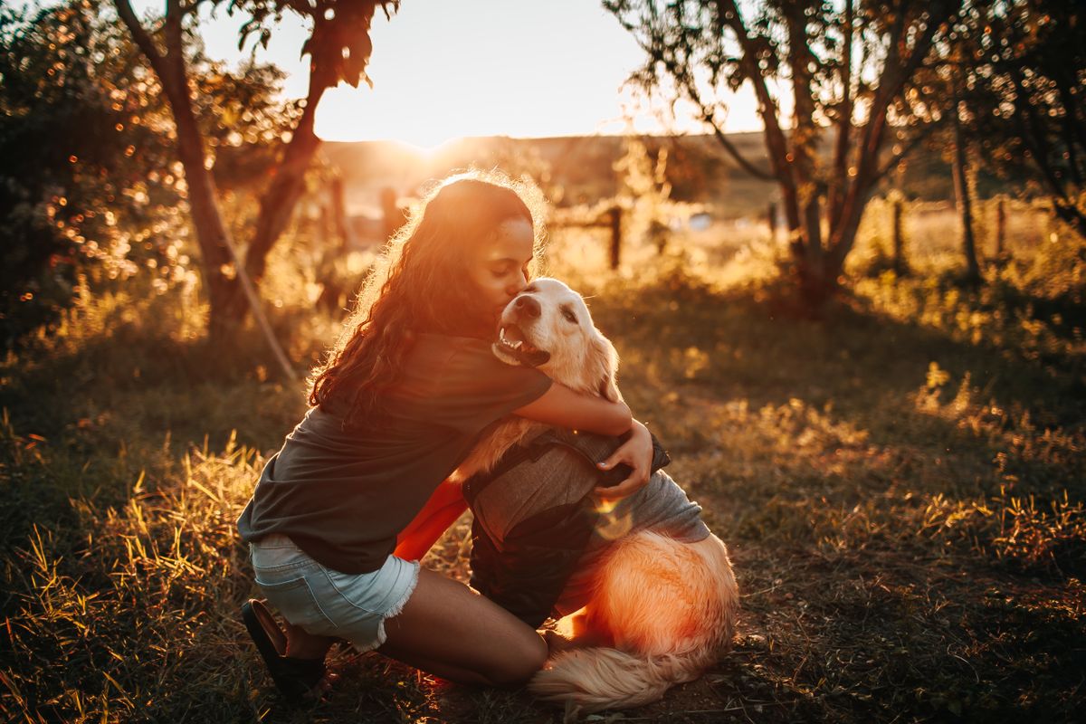 Young girl hugging a golden retriever in the countryside