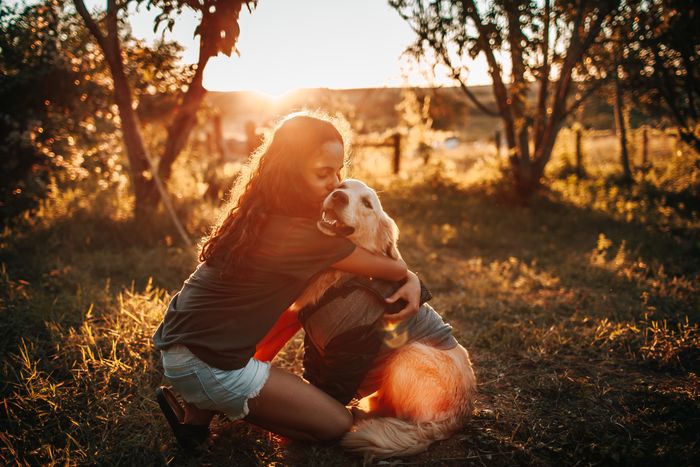 Young girl hugging a golden retriever in the countryside