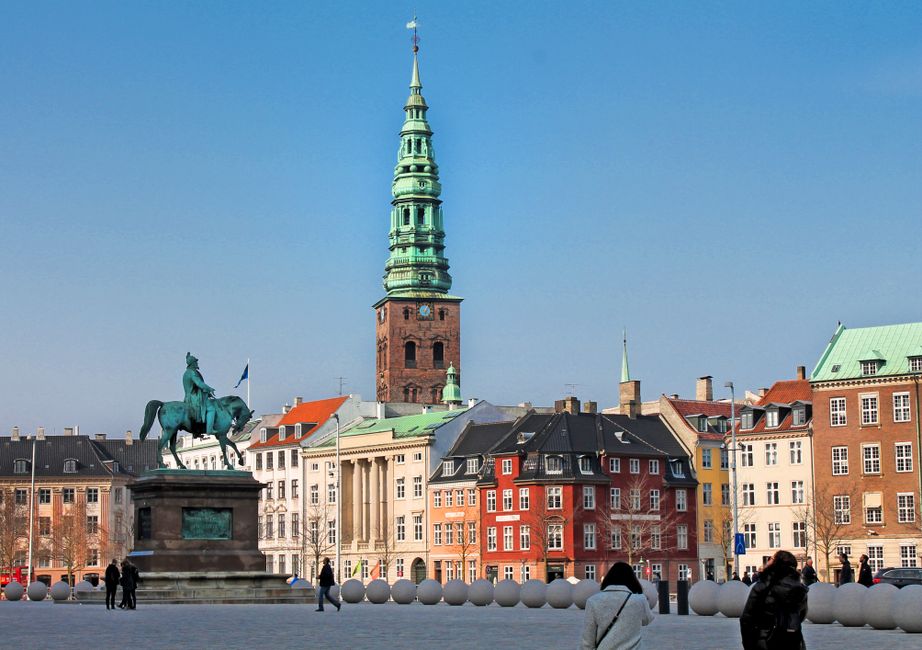 View of a colorful Copenhagen square featuring a historic equestrian statue and architectural landmarks.
